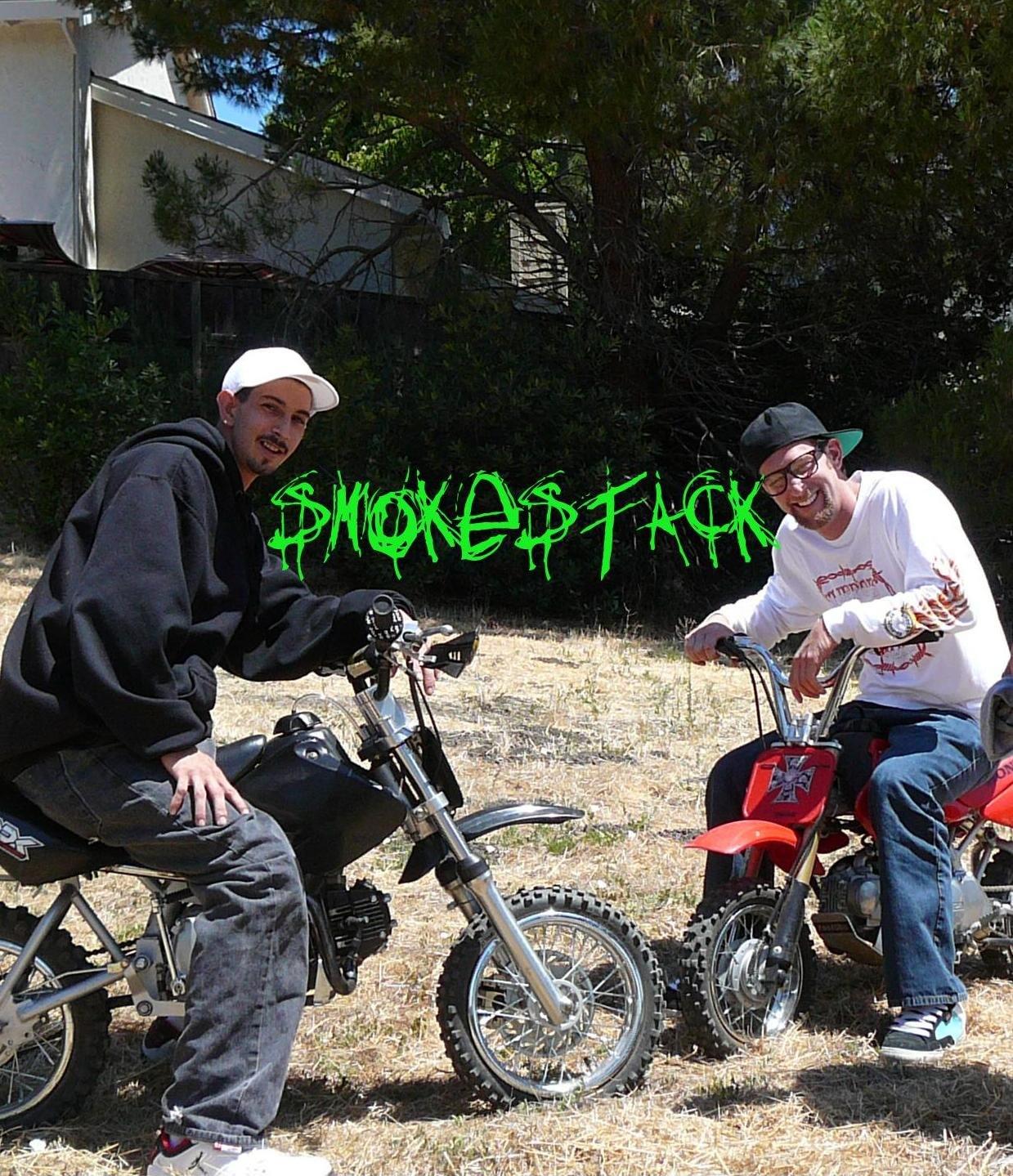 Two members of Smokestack Crew on dirt bikes in a dry field